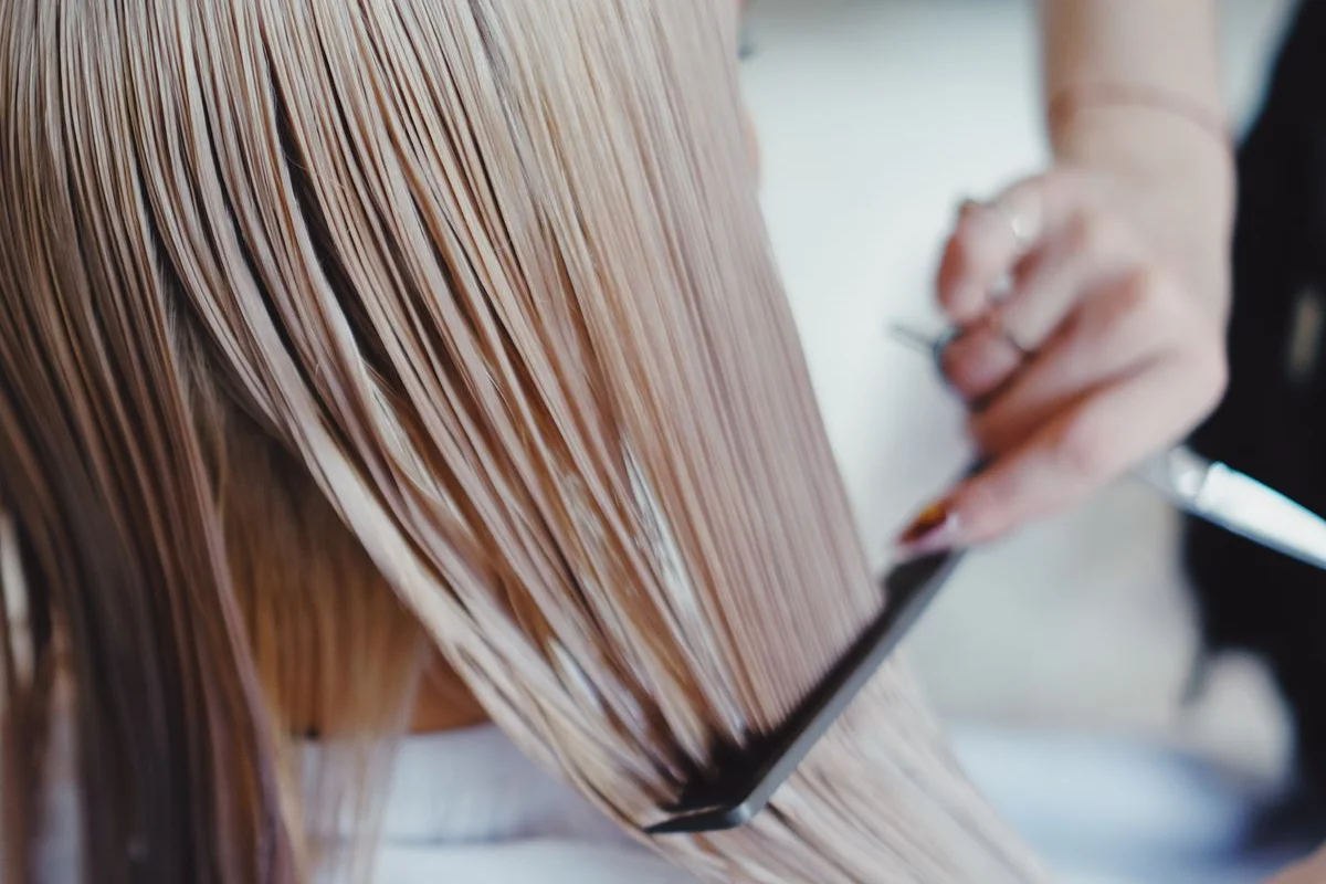 Stylist combing long straight hair in sections
