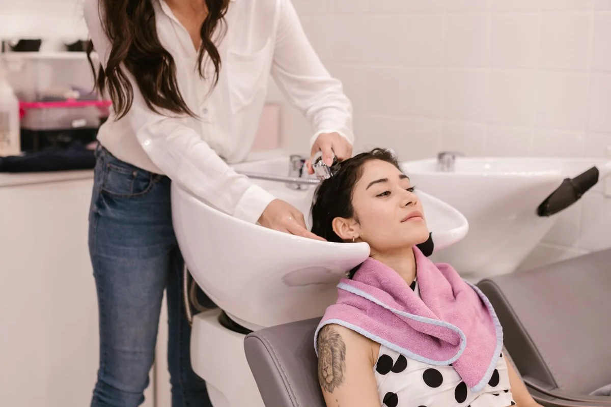 Stylist washing a client’s hair at the salon basin before a smoothing service