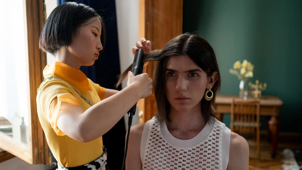 Hairdresser straightening a client’s long hair in the salon